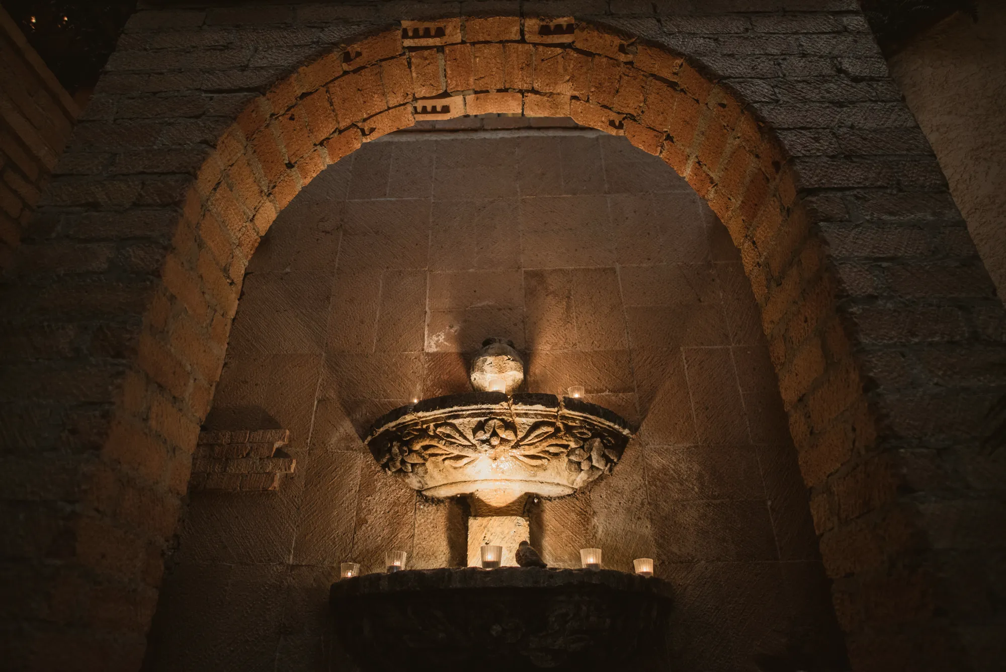 Candlelit chandelier inside a stone arch